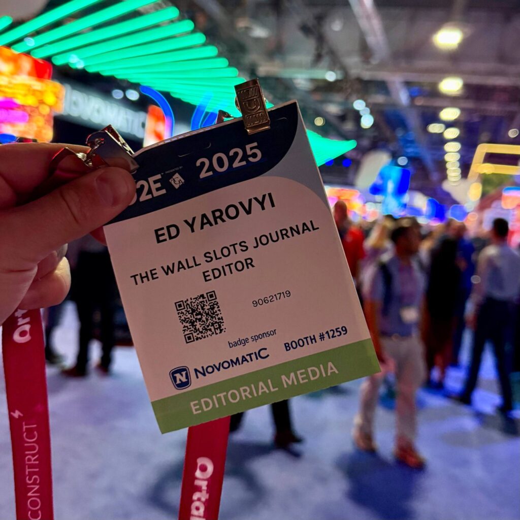 G2E 2025 Editorial Media badge at The Venetian Expo in Las Vegas, expo floor with LED booths and Novomatic in the background